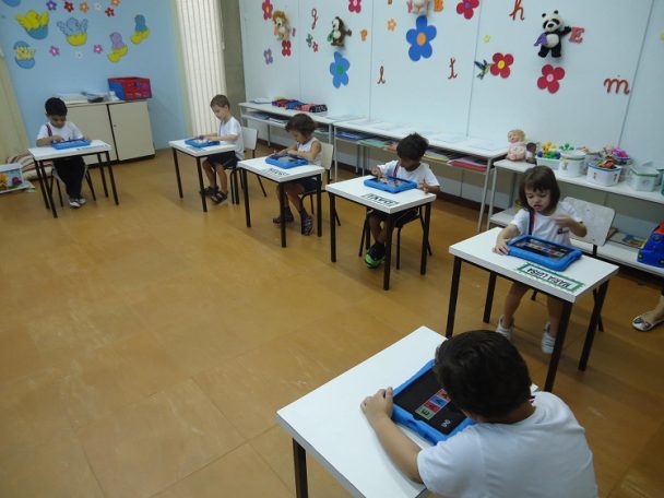 Sala de aula com alunos usando tablets nas carteiras
