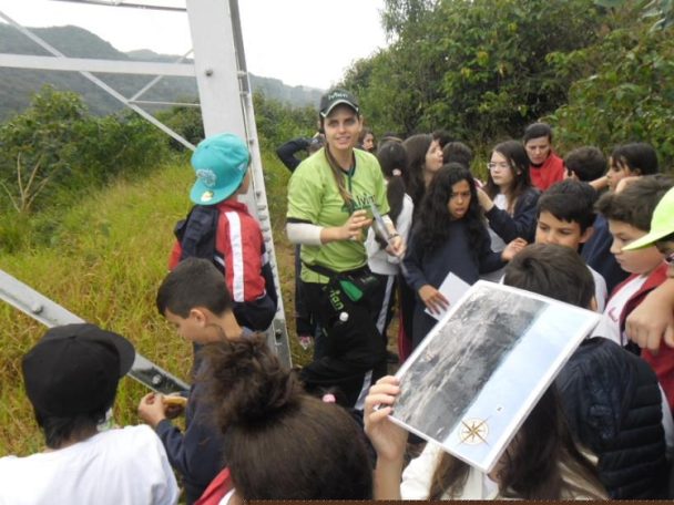 Alunos e monitor observando um material impresso durante a visita à Serra do Japi