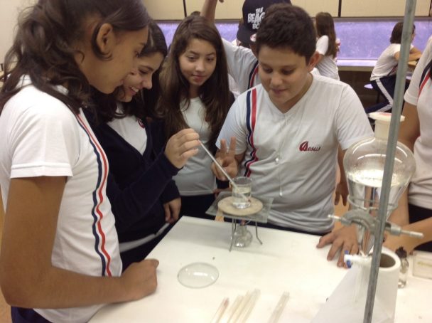 Alunos fazendo experimento com bico de Bunsen no laboratório, no projeto sobre sustentabilidade