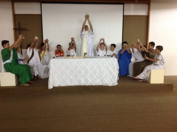 Encenação da Semana Santa no palco, com alunos de túnica diante do altar