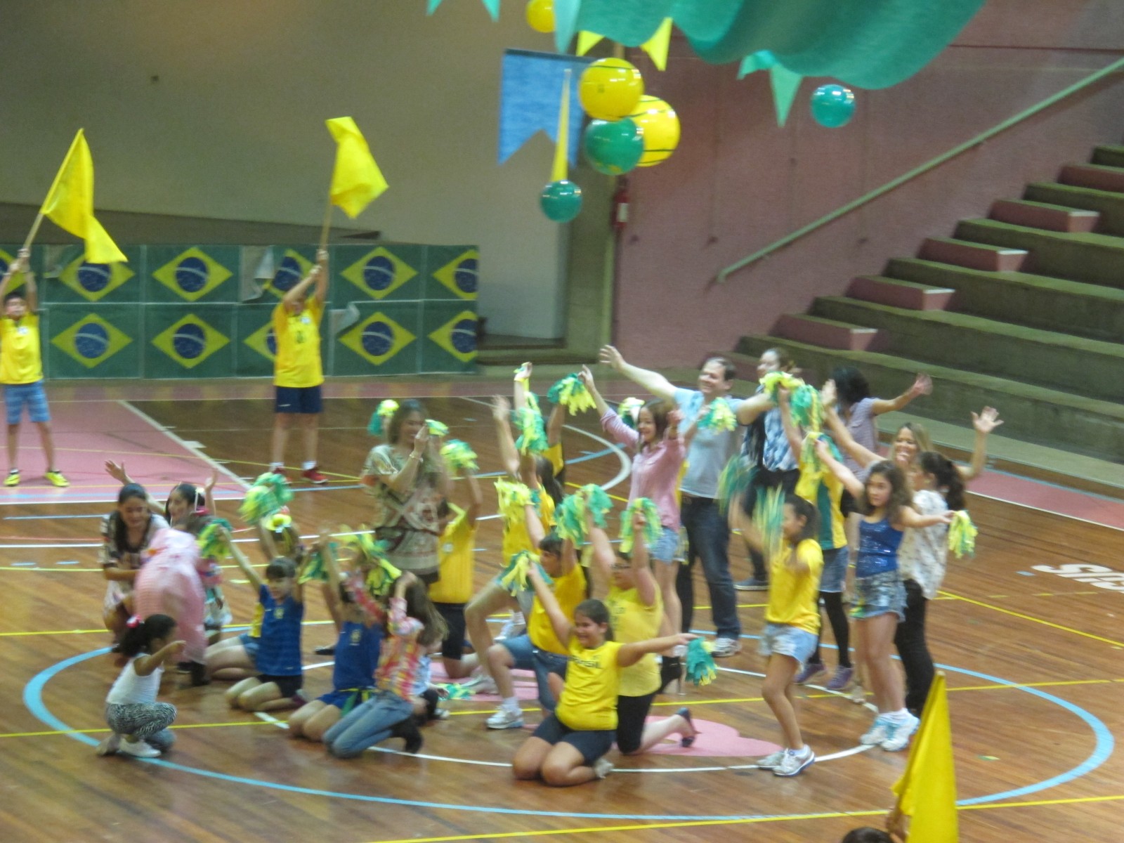 Alunos com bandeirinhas e balões no ginásio durante o Arraiá em Ritmo de Copa