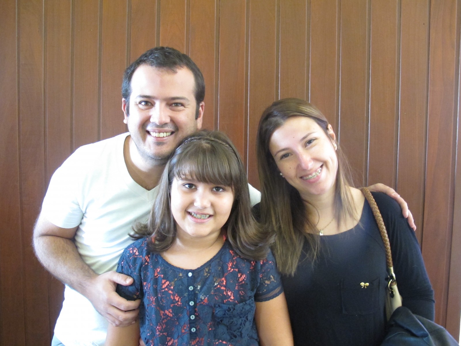 Pai, mãe e filha sorrindo juntos na comemoração do Dia dos Pais