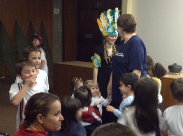 Crianças assistindo à apresentação do boi-bumbá com a professora segurando o boneco