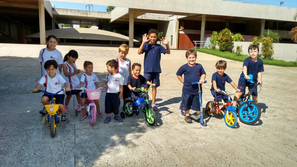 Crianças com bicicletas e triciclos no pátio externo, em foto de fevereiro