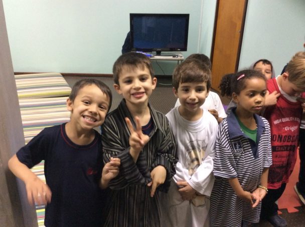 Grupo de meninos sorrindo e fazendo pose na sala, em foto de agosto