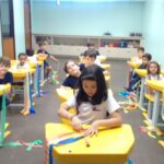 Crianças em atividade nas carteiras da sala, em foto de novembro