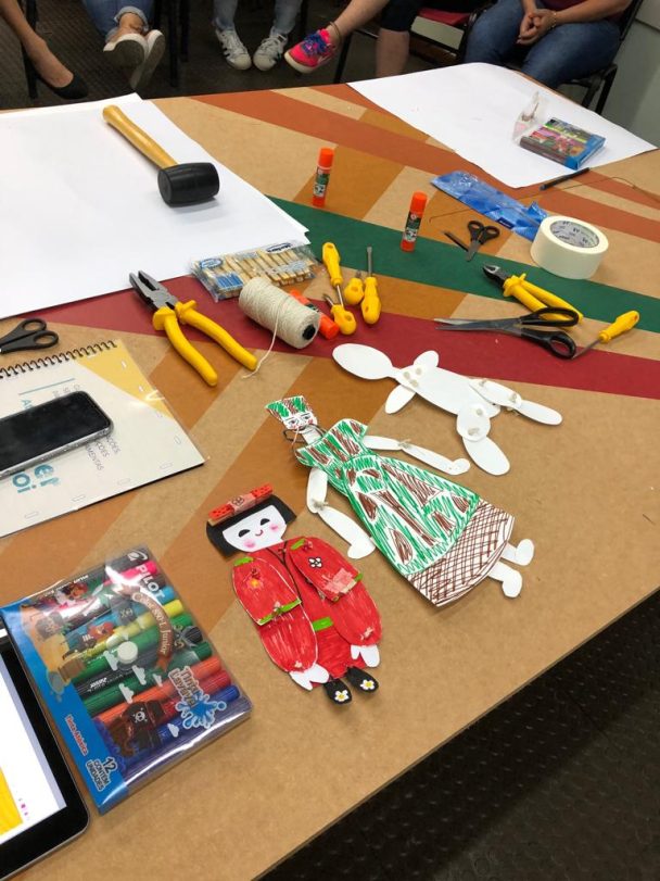 Mesa com ferramentas, papel e bonecos de artesanato na oficina Colocando a mão na massa