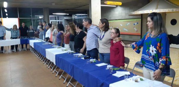 Famílias sendo atendidas em mesas enfileiradas durante a vivência da Ceia Pascal