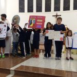 Alunos apresentam cartazes no altar durante a Novena de Santa Rita