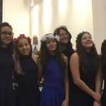 Alunos vestidos de branco em procissão pelo corredor da igreja, na Coroação de Nossa Senhora