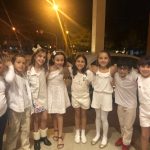 Alunos vestidos de branco em procissão pelo corredor da igreja, na Coroação de Nossa Senhora