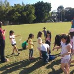 Crianças brincam com bolhas de sabão no gramado, na colônia Super Férias