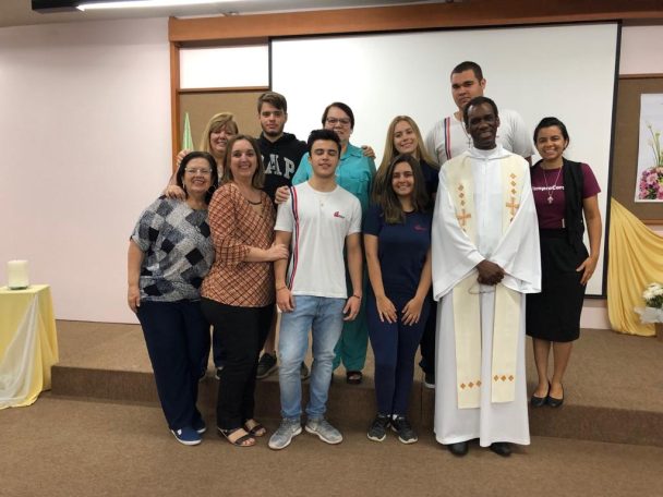 Famílias, alunos e o padre posando no salão durante a Semana Nossa Senhora do Calvário