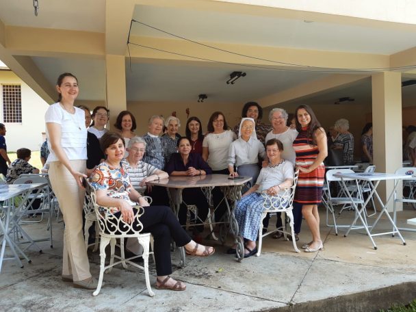 Convidadas reunidas em mesas no pátio na celebração da Festa de Nossa Senhora do Calvário