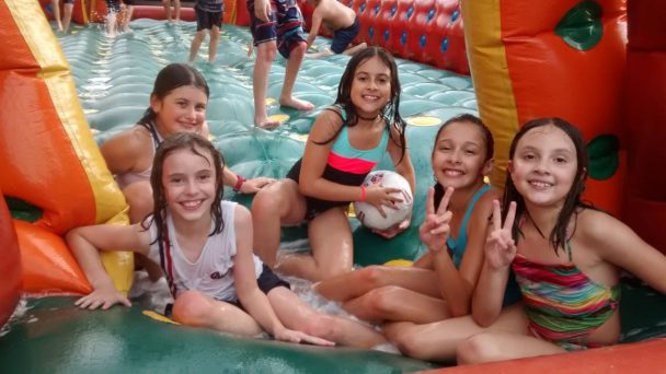 Alunas sorrindo dentro da piscina com brinquedos infláveis no Dia das Crianças