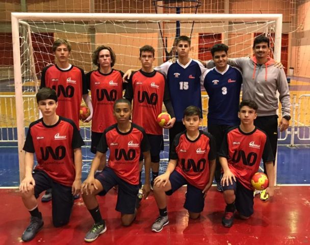 Time de futsal do colégio posando com a bola diante do gol após a conquista do campeonato