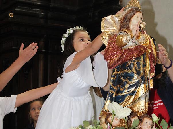 Aluna de branco coroando a imagem de Nossa Senhora na celebração Te coroamos, oh Mãe, nossa Rainha
