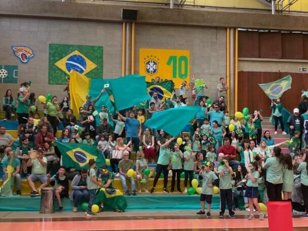 Alunos com bandeiras do Brasil e camisas verdes na abertura da Semana de Esportes