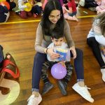 Mãe e filho sentados no chão do ginásio durante a homenagem do Dia das Mães