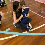Mãe e filho sentados no chão do ginásio durante a homenagem do Dia das Mães