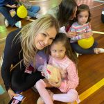 Mãe e filho sentados no chão do ginásio durante a homenagem do Dia das Mães