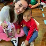 Mãe e filho sentados no chão do ginásio durante a homenagem do Dia das Mães
