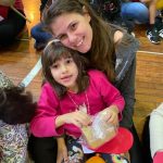 Mãe e filho sentados no chão do ginásio durante a homenagem do Dia das Mães