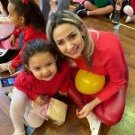 Mãe e filho sentados no chão do ginásio durante a homenagem do Dia das Mães