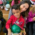 Mãe e filho sentados no chão do ginásio durante a homenagem do Dia das Mães