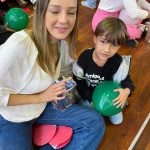 Mãe e filho sentados no chão do ginásio durante a homenagem do Dia das Mães