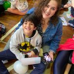 Mãe e filho sentados no chão do ginásio durante a homenagem do Dia das Mães