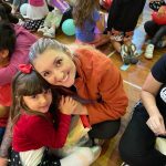 Mãe e filho sentados no chão do ginásio durante a homenagem do Dia das Mães