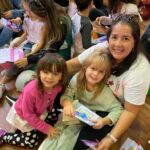 Professora e crianças sentadas no chão com os presentes da homenagem do Dia das Mães