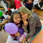 Mãe e filho sentados no chão do ginásio durante a homenagem do Dia das Mães