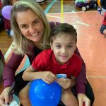 Mãe e filho sentados no chão do ginásio durante a homenagem do Dia das Mães