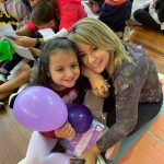 Mãe e filho sentados no chão do ginásio durante a homenagem do Dia das Mães