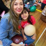 Mãe e filho sentados no chão do ginásio durante a homenagem do Dia das Mães