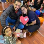 Mãe e filho sentados no chão do ginásio durante a homenagem do Dia das Mães