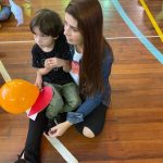 Mãe e filho sentados no chão do ginásio durante a homenagem do Dia das Mães