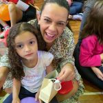 Mãe e filho sentados no chão do ginásio durante a homenagem do Dia das Mães