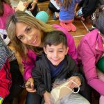 Mãe e filho sentados no chão do ginásio durante a homenagem do Dia das Mães