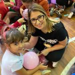 Mãe e filho sentados no chão do ginásio durante a homenagem do Dia das Mães