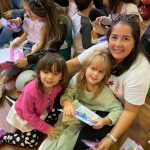 Mãe e filho sentados no chão do ginásio durante a homenagem do Dia das Mães
