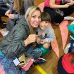 Mãe e filho sentados no chão do ginásio durante a homenagem do Dia das Mães