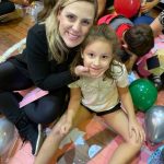 Mãe e filho sentados no chão do ginásio durante a homenagem do Dia das Mães