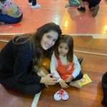 Mãe e filho sentados no chão do ginásio durante a homenagem do Dia das Mães
