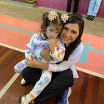 Mãe e filho sentados no chão do ginásio durante a homenagem do Dia das Mães