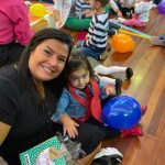 Mãe e filho sentados no chão do ginásio durante a homenagem do Dia das Mães
