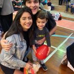 Mãe e filho sentados no chão do ginásio durante a homenagem do Dia das Mães