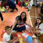 Mãe e filho sentados no chão do ginásio durante a homenagem do Dia das Mães